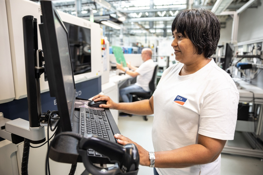 At the PC, Sujethini Arnold inspects a circuit board produced at SMA's electronics manufacturing facility.