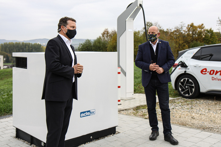 CEO Thomas Speidel and Minister of Transport Winfried Hermann at the HPC, while the VW ID.3 is charging in the background.