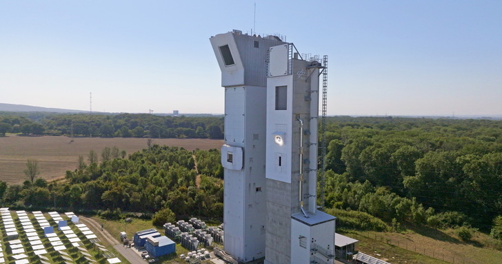 The mirror field concentrates the radiation on the DLR multifocus solar tower. There, brightly illuminated, the Synhelion solar receiver can be seen.