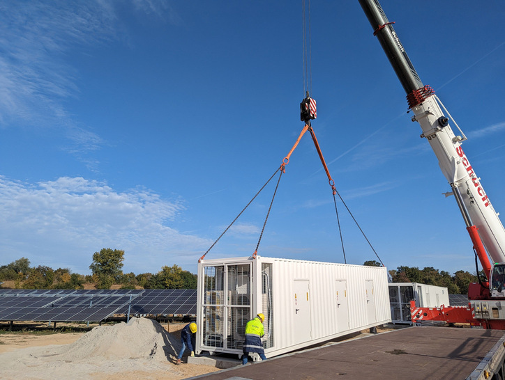 The battery storage system for the solar park in Bruchsal, Germany is delivered and lifted onto the foundation with a heavy-duty crane.