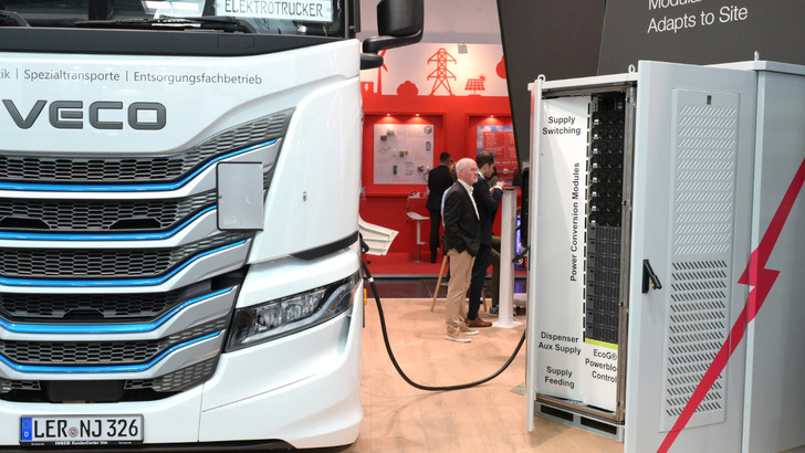 An Iveco e-truck takes a sip from a megawatt charger at the trade fair stand