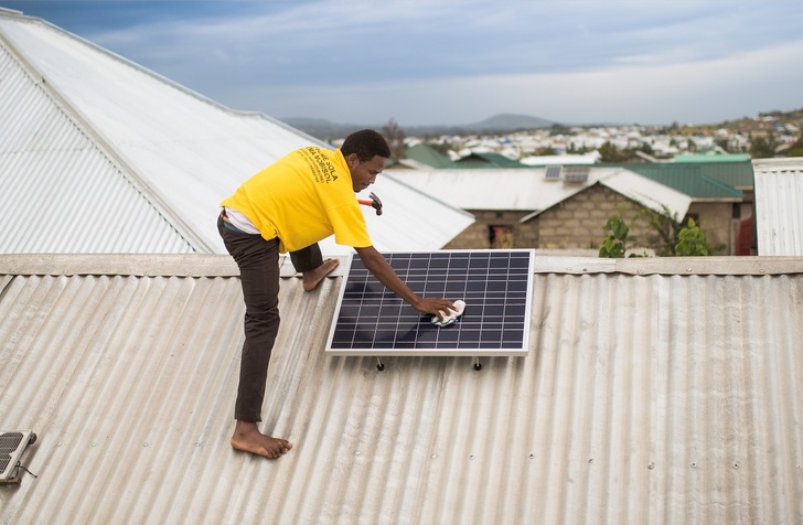 Installation of a small Mobisol system`s panel on corrugated iron roof. - © Mobilsol
