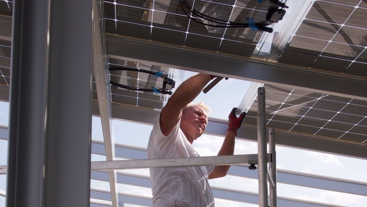 Installing the glas-glass-modules on top of the carport.