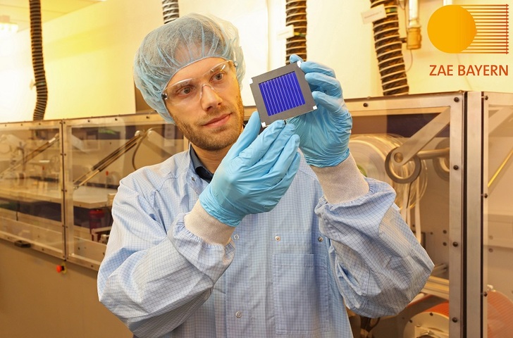Andreas Distler (ZAE Bayern) with the organic record solar module at the Solar Factory of the Future. In the background, the pilot line for printed thin-film photovoltaics. - © ZAE/Kurt Fuchs
