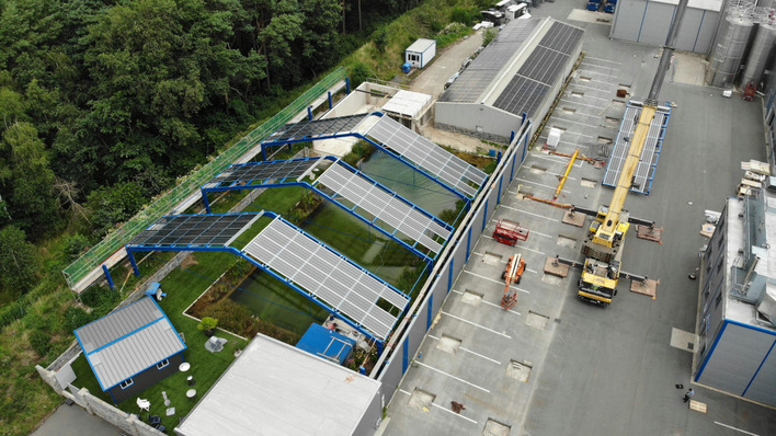 A crane lifted the tubular steel base frame onto the edge of the basin.