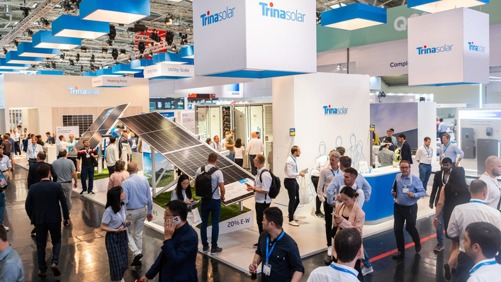 People attend a busy Trina Solar exhibition booth showcasing solar panels at an indoor trade show. - © Trina Solar