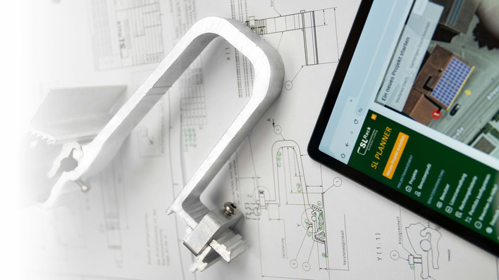 A metal clamp, technical drawings, and a tablet displaying a planning website are on a white surface. - © SL Rack